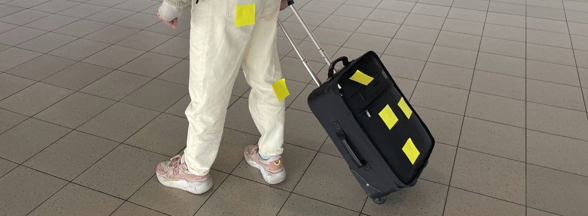 Een persoon met rolkoffer waarop Post-its zijn geplakt. Hoe kunnen we tourisme ontwerpen