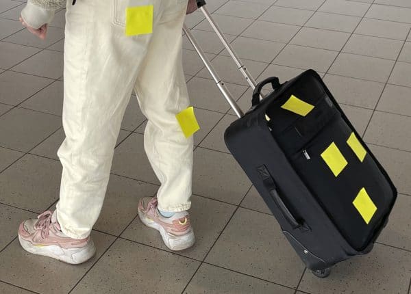 Een persoon met rolkoffer waarop Post-its zijn geplakt. Hoe kunnen we tourisme ontwerpen